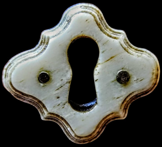 Curvy diamond shaped carved bone keyhole escutcheon.