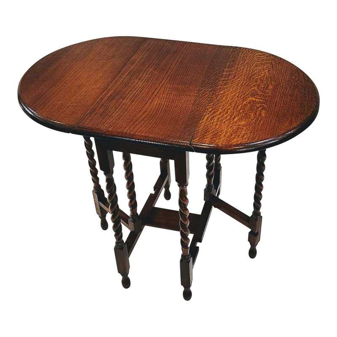 Petite oval drop-leaf table is ideal for smaller space living!  Antique English burl figured oak table easily extends by lifting its two leaves and swinging its gate-legs into place underneath.  The eight English brown oak legs have been turned into a barley sugar twist.