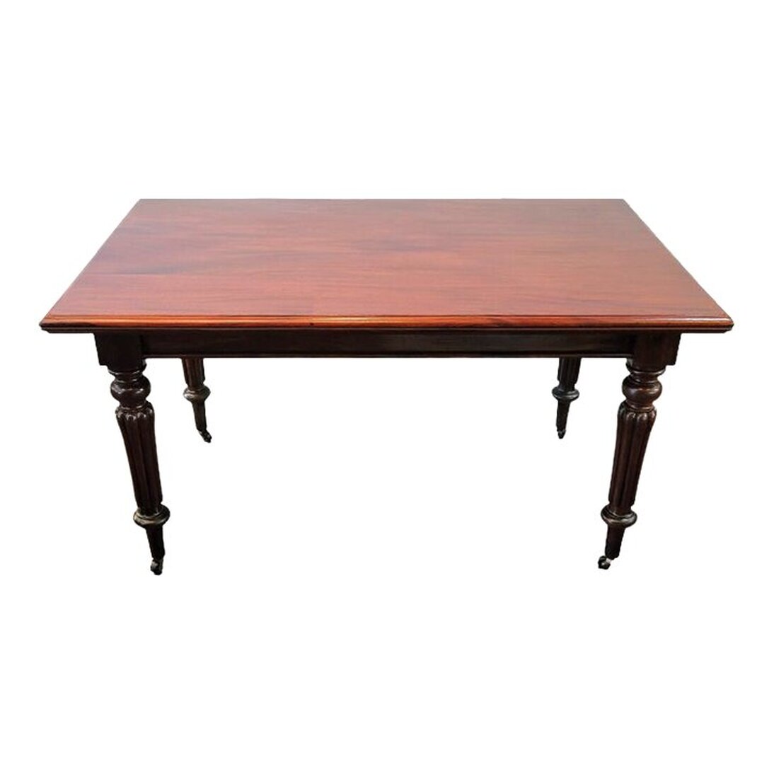 Antique Santo Domingo mahogany table attributed to Gillows of Lancaster works perfectly as a library table, dining table, café table, writing desk, and work table.  The molded-edge rectangular table top shows off the beautiful qualities of Santo Domingo mahogany wood - the rich color, burled figure, and distinctive ribbon grain common to mahogany.  The plain apron has a molded bottom edge.  The four corner blocks surmount the turned, ringed, and tapered legs. The legs are reeded through the middle. The legs end in tapered arrow feet on castors.  57.25