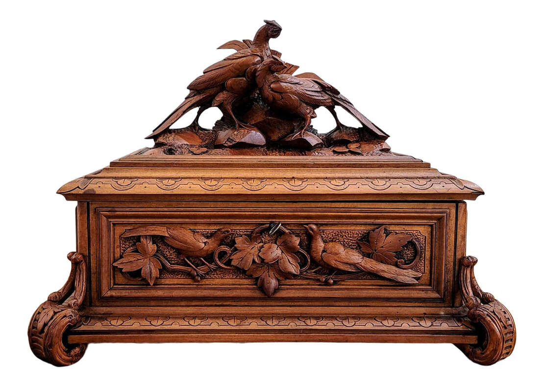 Late-19th century Swiss Schwerzwald / Black Forest carved linden wood box.  The hinged lid is topped with a pair of of pheasant birds in a natural setting of earth, stone, and foliage.  The front panel of the box is relief carved with a pair of pheasant birds sitting on grape vines and surrounded by grape leaves.  The sides are relief carved with grapes, grape vines, and grape leaves.  The back panel is plain.  The top and bottom edged are trefoils and cyma curves.  The box rests upon four s-curved line-carved feet into which are carved leaves and branch surface treatment.  The interior is lined with cerulean blue silk fabric.