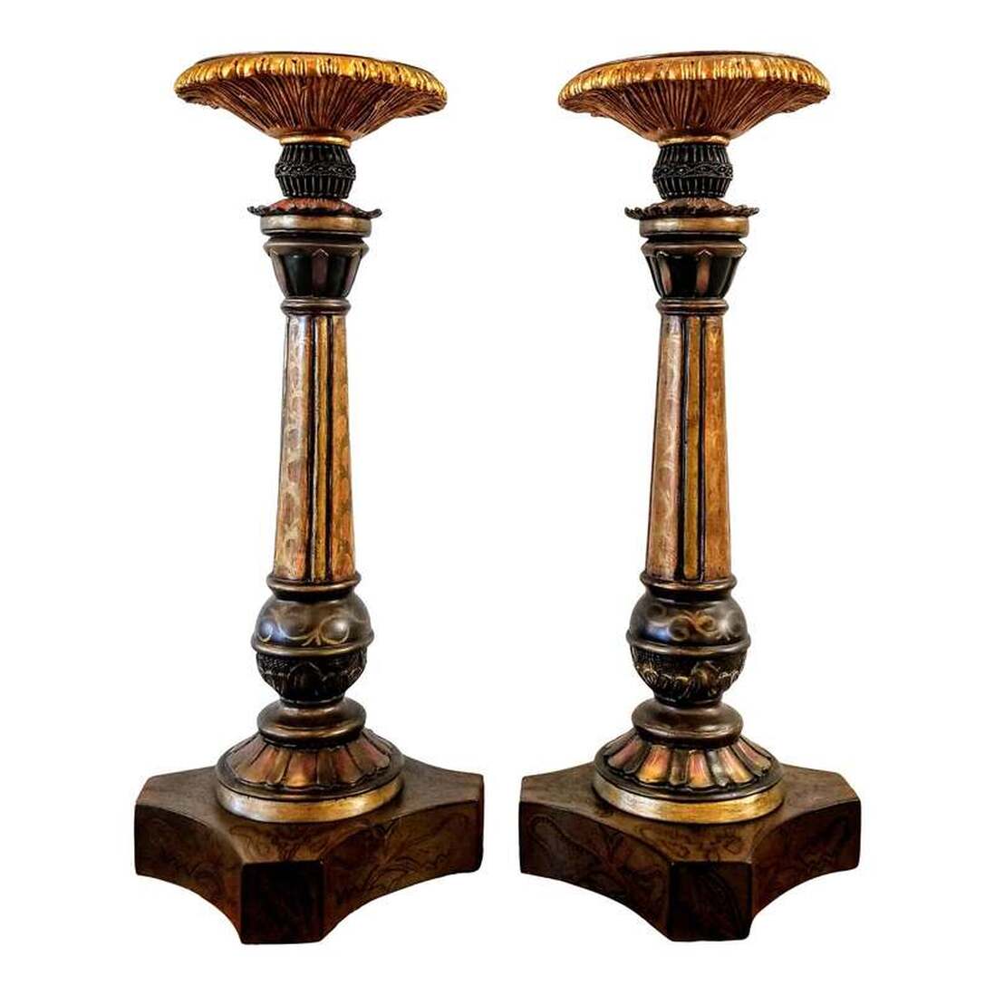 John-Richard has been designing for the luxury interior decoration market since 1980.  This pair of post-1980 large weighted candlesticks are constructed of painted metal, wood, and resin.  The heavy duty candlesticks are painted in tones of gold, black, red, and Spanish green.  The design is a banister style featuring stylized nods to fluting, modelling, cup-and-cover, and egg-and-dart. The candlesticks will complement furnishings from the John-Richard subsidiary Alexander and Mary and will be a whimsical addition to Classical, Jacobean, Carolean, William and Mary, and Renaissance interiors.  A sticker on the bottom states 