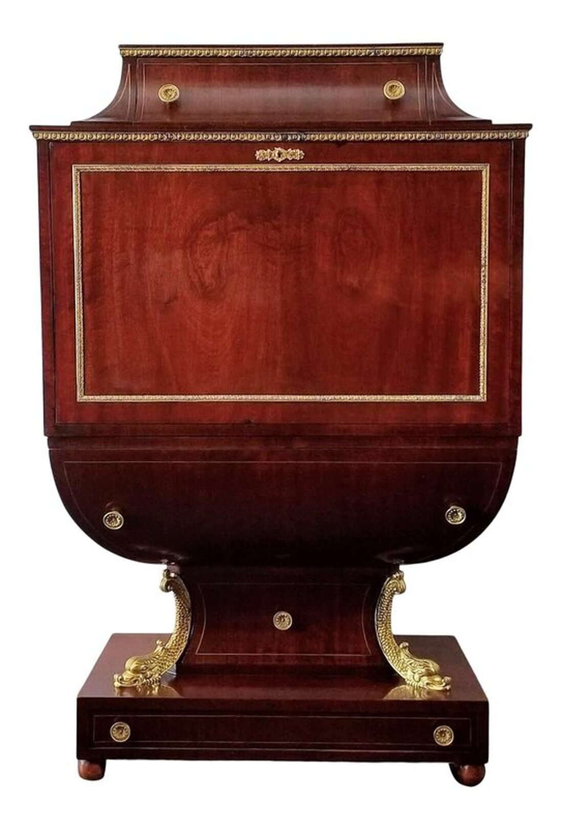 Replica of early 19th century secretary, or fall front, desk ( secrétaire à abattant ) in the French Empire / Viennese and Austrian Biedermeier style finished with mahogany veneers and chased brass mounts.  Under the chased brass trim at the top is a single drawer with two chrysanthemum chased pulls and inlaid brass banding. Brass banding is also inset to the sides of the drawer.  The drop front is located below more chased brass trim. The panel is framed with chased brass trim and there is a chased brass key scutcheon at top.  The interior is fitted with eight small storage drawers - four on either side of the central cabinet. The drawers feature inset brass banding and laurel wreath drop pulls. Below the central cabinet is one long drawer with inlaid brass banding and two laurel wreath drop pulls. The shaped door at center is framed and inlaid with brass banding. The open door reveals a hidden cocktail cabinet with one glass shelf and mirrored back. The writing and work surface of the drop front panel is inset with embossed gold decoration on green leather.  The possum belly drawer below the drop panel is edged with inset brass banding and has two chrysanthemum chased brass pulls.  The base has one shaped drawer with a chrysanthemum chased brass pull and inlaid brass banding. On each side of this drawer are gilt dolphins.  At the bottom, above the bun feet, is one long drawer with two chrysanthemum chased pulls and inlaid brass banding.