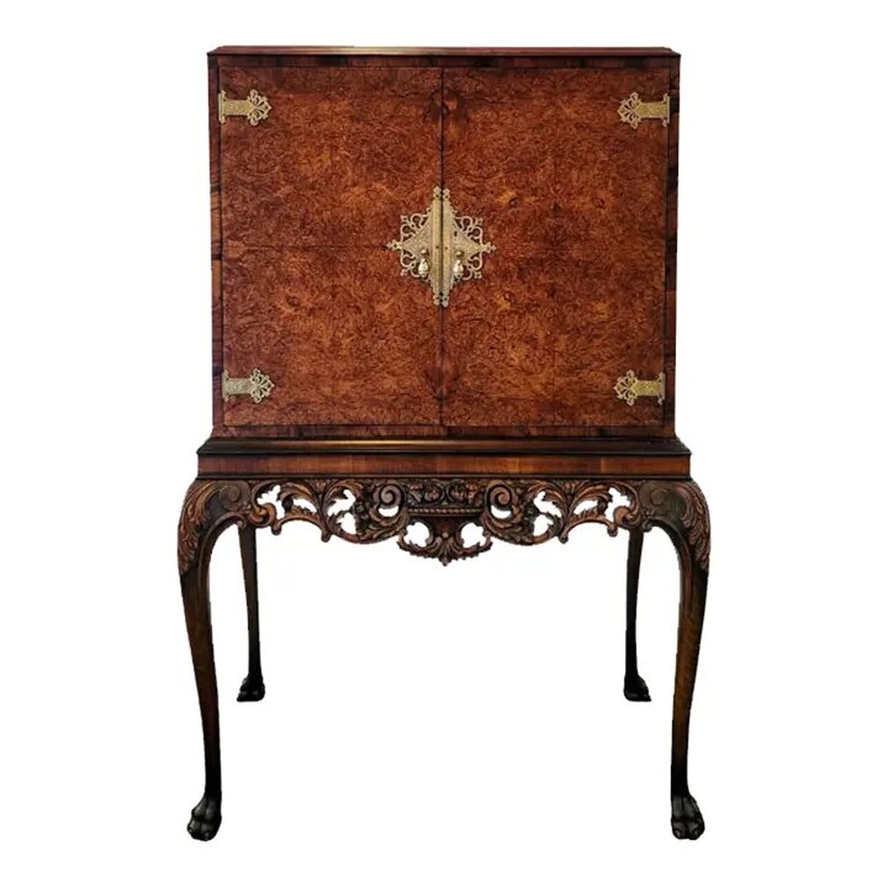 Early 20th century Queen Anne style cocktail cabinet on stand by Hille of London.  The cabinet is constructed of burl English walnut with burr walnut veneer on the two front doors.  The top is flat, allowing for use as a storage shelf.  The doors are embellished with etched brass strap hinges, escutcheons, and teardrop pulls.  The interior of the drinks cabinet is lined with sycamore wood, features a mirrored back and base, two glass shelves, and a mirrored slide-out prep station.  The mirror on the bottom may be removed for cleaning the wood base when needed.  The two glass shelves are removable.  The stand's apron is embellished with neoclassic style carvings of scrolls, swags, acanthus leaves, and a basket of flowers at the center.  The cabriole legs are embellished with carvings of acanthus leaves on the knees. The legs end in hairy paw and claw feet.  The carvings are well-done and finely detailed.  The drinks cabinet will complement interiors featuring elements of Georgian, Queen Anne, Chippendale, Chinoiserie, and Baroque.  Cocktail cabinet is in stock now at India Street Antiques in San Diego and is ready for pick-up, delivery, and shipping.