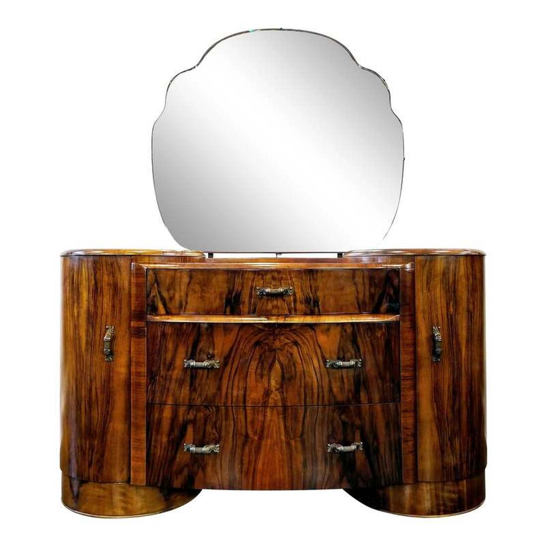 Vintage Art Deco style burl walnut vanity with shaped, tilting mirror manufactured by Shrager Brothers Masterpiece Furniture on Bridport Road in Edmonton, London, England.  Vanity has three center storage drawers with stylized Neoclassical column and acanthus leaf pulls. Each rounded side has a storage cabinet with shelves built out from the inside of the doors.  The shaped mirror may be easily tilted by a finger pull at the bottom front of the mirror.  The Masterpiece Furniture label on the back lists this vanity as serial number 7463.  The Shrager Furniture medallion is inside the right side door.  Measurements:  51